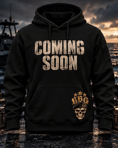 Black hoodie with Coming Soon across the chest and the RBG skull-in-beret on the hem, on a boat deck at dusk